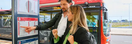 Twee mensen die de bus reistijd bekijken van AllGo